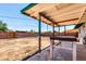 Covered patio over looking a large dirt backyard with a brick wall, wooden gate, and a table for outdoor dining at 539 E Pebble Beach Dr, Tempe, AZ 85282