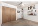 Bright carpeted bedroom featuring a ceiling fan, ample lighting, shelving, and closet space at 539 E Pebble Beach Dr, Tempe, AZ 85282