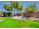 Picturesque backyard with lush green lawn, mature trees, and a circular patio featuring a fire pit at 549 E Quentin Ln, San Tan Valley, AZ 85140