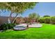 Lush backyard with a circular patio and a built-in fire pit, great for outdoor entertaining and relaxation at 549 E Quentin Ln, San Tan Valley, AZ 85140