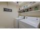 Functional laundry room with modern washer and dryer units and storage shelving at 549 E Quentin Ln, San Tan Valley, AZ 85140