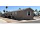 Tan mobile home with desert landscaping, a covered carport, and multiple windows at 625 W Mckellips Rd # 358, Mesa, AZ 85201