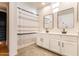 Bathroom with dual sinks, white cabinets, decorative mirrors, and a shower with striped curtain at 706 E Washington St # 124, Phoenix, AZ 85034