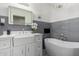 Elegant bathroom with chandelier, gray tile accent wall, garden tub, and granite countertop sink at 7731 E Rose Ln, Scottsdale, AZ 85250