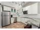 Bright kitchen with white cabinets, granite countertops, stainless steel appliances, and a bar area at 7731 E Rose Ln, Scottsdale, AZ 85250
