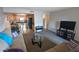 A living room with tan colored couches, a view into the kitchen, and a dark television with a display stand at 7910 E Camelback Rd # 302, Scottsdale, AZ 85251
