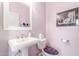 Powder room with pedestal sink, decorative mirror and lilac-painted walls at 905 S Osborn Ln, Gilbert, AZ 85296