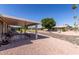 Spacious backyard with a covered patio area and gravel landscaping under a blue sky at 10439 W Kingswood Cir, Sun City, AZ 85351