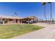 Attractive single-story home boasting a covered carport, well-maintained lawn, and vibrant desert landscaping at 10439 W Kingswood Cir, Sun City, AZ 85351