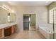 Expansive primary bath features tiled floors, separate vanities, a soaking tub, and a glass enclosed shower at 13657 W Holly St, Goodyear, AZ 85395