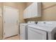 Bright laundry room featuring a white washer and dryer set with storage cabinets above for convenience at 13657 W Holly St, Goodyear, AZ 85395