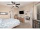 Spacious bedroom featuring a large bed, ceiling fan, and a view of the living room through the doorway at 14575 W Mountain View Blvd # 12309, Surprise, AZ 85374