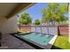 Charming pool features brick and tile wall feature, lush artificial turf and shade trees at 14759 W Alexandria Way, Surprise, AZ 85379