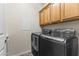 Laundry room featuring updated washer and dryer units with storage cabinets above for optimal convenience at 16762 W Sonora St, Goodyear, AZ 85338