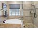 A bright bathroom with a tub, glass block window, and updated shower with a seat and tiled walls at 1720 W Aloe Vera Dr, Phoenix, AZ 85085