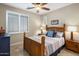 Comfortable bedroom with a ceiling fan, window with shutters, and a beautifully made wooden bed frame at 1720 W Aloe Vera Dr, Phoenix, AZ 85085