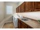 Spacious laundry room with a washing machine, dryer, sink, and lots of storage in wooden cabinets at 1720 W Aloe Vera Dr, Phoenix, AZ 85085