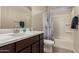 Well-lit bathroom with a single sink vanity and a shower over the tub with nautical-themed shower curtain at 17444 W Via De Luna Dr, Surprise, AZ 85387