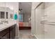 Modern bathroom with a glass-enclosed shower, double vanity, and views into the main bedroom at 17444 W Via De Luna Dr, Surprise, AZ 85387