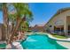 Serene backyard featuring a sparkling pool, mature palms, putting green, and cozy lounge area at 17796 W Andora St, Surprise, AZ 85388
