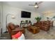 Comfortable living room featuring leather seating, a modern ceiling fan, and stylish decor with tile flooring at 18027 W Tina Ln, Surprise, AZ 85387