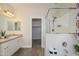 Bright main bathroom featuring double sinks, a soaking tub with a shower, and access to a walk-in closet at 18027 W Tina Ln, Surprise, AZ 85387
