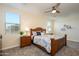 Bright main bedroom showcases a wooden bed frame, soft carpeting, and natural light from large windows at 18027 W Tina Ln, Surprise, AZ 85387
