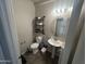 Functional half-bathroom featuring a pedestal sink, toilet, and a wall-mounted shelving unit at 1814 W Minton St, Phoenix, AZ 85041