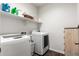 Laundry room featuring newer front load washer and dryer and overhead shelving at 19531 W Palo Verde Dr, Litchfield Park, AZ 85340