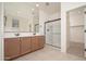 Bathroom featuring dual sinks, a large mirror, and a walk-in shower with glass doors at 1965 N 213Th Dr, Buckeye, AZ 85396