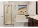 Bathroom featuring a glass shower enclosure, tub, vanity with storage, and natural light from the window at 19889 W Sherman St, Buckeye, AZ 85326