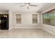 Open-concept living room featuring tile flooring, neutral paint, ceiling fan, and two large windows with blinds at 19889 W Sherman St, Buckeye, AZ 85326