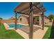 Inviting backyard pool with pergola-covered patio and lush artificial turf, perfect for outdoor relaxation and entertainment at 19889 W Sherman St, Buckeye, AZ 85326