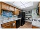 A functional kitchen displays wood cabinetry, an undermount sink, black appliances, and open shelving for storage and display at 212 Leisure World --, Mesa, AZ 85206