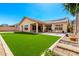 Beautiful backyard with manicured artificial lawn, landscaped garden beds, and a covered patio area at 27713 N 57Th Dr, Phoenix, AZ 85083