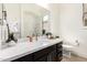 Elegant bathroom with a large mirror, white countertops, dark wood cabinets, and modern fixtures at 27713 N 57Th Dr, Phoenix, AZ 85083