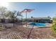Beautiful backyard featuring a refreshing pool, shade umbrella, metal fencing and well-maintained landscaping, perfect for outdoor enjoyment at 325 E Harmony Ave, Mesa, AZ 85210
