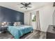Cozy bedroom featuring a blue accent wall, ceiling fan, and wood-look flooring at 325 E Harmony Ave, Mesa, AZ 85210