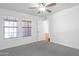 This bright bedroom has gray carpet, a ceiling fan, and two windows at 4225 E Sandia St, Phoenix, AZ 85044