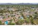 Aerial view displays a home with a private pool, desert landscaping, and neighboring residences amidst green trees at 6102 E Aster Dr, Scottsdale, AZ 85254