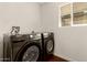 Modern laundry room features sleek Samsung washer and dryer with a window for natural light at 6820 E Pinchot Ave, Scottsdale, AZ 85251