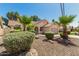 Charming single-story home with well-maintained landscaping, desert rock, mature palm trees, and a red tile roof at 7139 W Mcrae Way, Glendale, AZ 85308