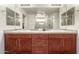 Bathroom featuring double sinks, wood cabinets, and a large mirror above a tile countertop at 7858 W Fetlock Trl, Peoria, AZ 85383