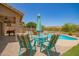 Inviting outdoor seating area with colorful chairs and a table next to a sparkling pool, perfect for relaxing at 7858 W Fetlock Trl, Peoria, AZ 85383
