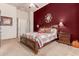 Cozy bedroom featuring a red accent wall, decorative mirror, and plush bedding and access to the ensuite bathroom at 8304 E Inca St, Mesa, AZ 85207
