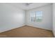 This bedroom has a ceiling fan, a large window, and carpet flooring at 9372 W Louise Dr, Peoria, AZ 85383