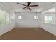 Well-lit bedroom with white walls, carpeted floor, natural light from the windows, and a ceiling fan at 9372 W Louise Dr, Peoria, AZ 85383