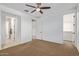 A bright bedroom features a ceiling fan, neutral carpet, and ample closet space at 9372 W Louise Dr, Peoria, AZ 85383