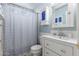 Bathroom features a white vanity, cabinet, mirror, and shower with patterned curtain at 9714 N 55Th Dr, Glendale, AZ 85302