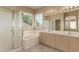 Bathroom features double sinks, tub, glass enclosed shower, and large mirror with vanity lighting at 986 W Citrus Way, Chandler, AZ 85248